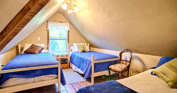 Cozy attic bedroom with three twin beds.
